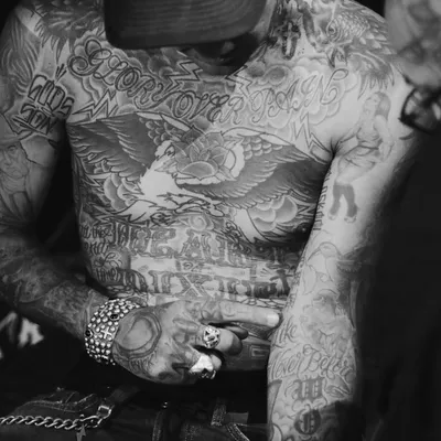Homme au torse entièrement tatoué, aigle et lettrages, en noir et blanc